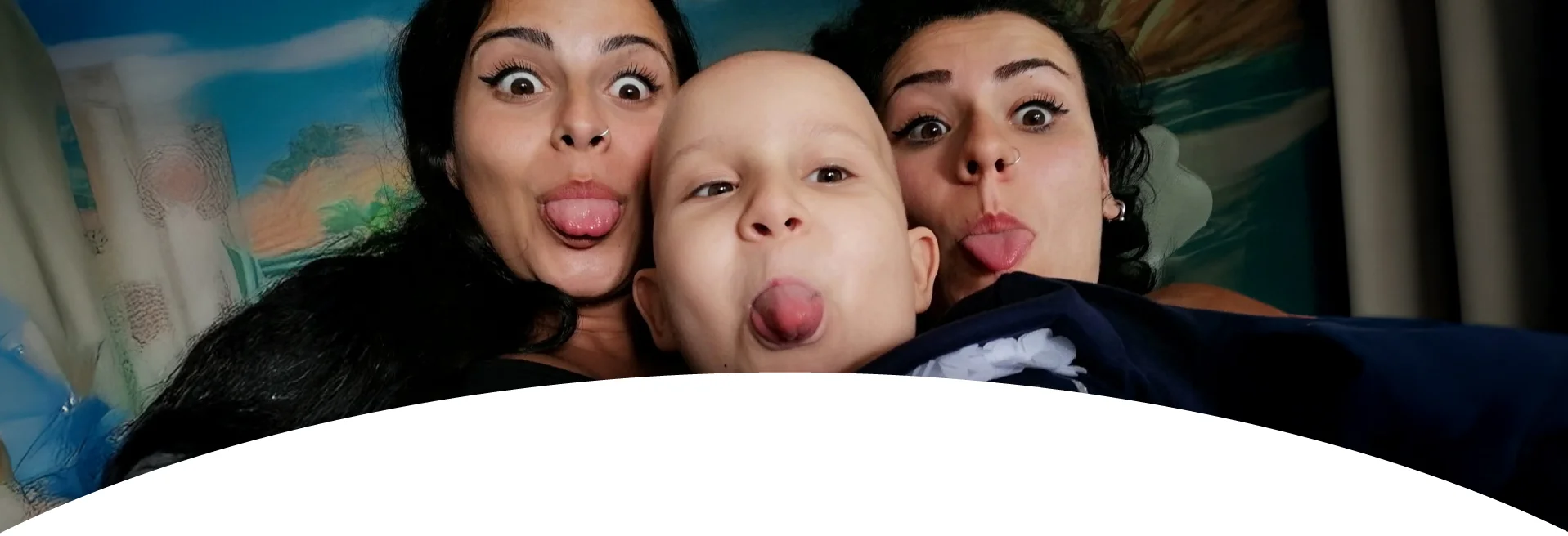 Giulia e Martina scherzano con un giovane paziente facendo la linguaccia